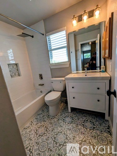 A bathroom with a toilet, sink, and a mirror.