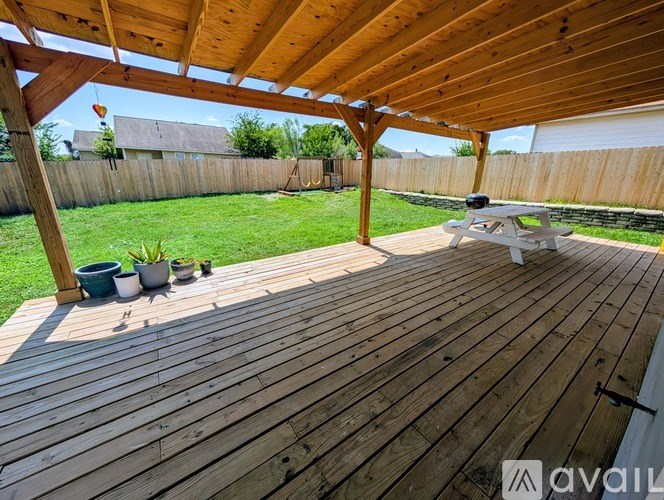 A wooden deck with a picnic table and potted plants.