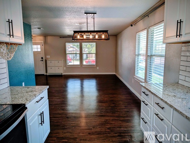 A kitchen with wooden floors and white cabinets.