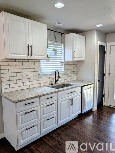 A kitchen with white cabinets and a granite countertop.