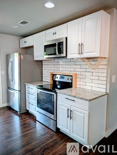 A kitchen with white cabinets and a refrigerator.