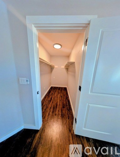 A hallway with a white door and wooden floor.