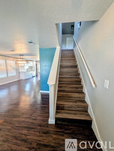 A wooden staircase with white railings leads to a second floor.