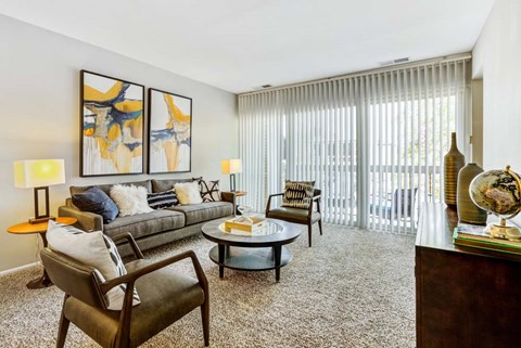 A living room with a grey couch, a coffee table, a chair, and a painting on the wall.