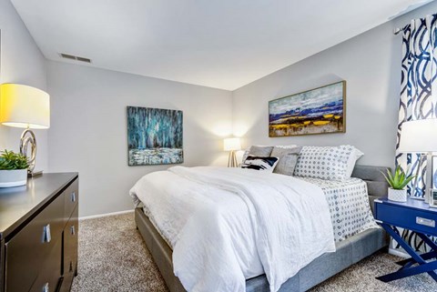 A bedroom with a bed, nightstand, and two lamps.