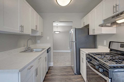 A kitchen with white cabinets and a stainless steel refrigerator.