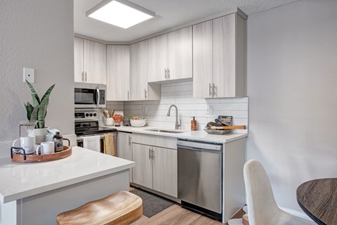 A modern kitchen with a stainless steel dishwasher and white countertops.