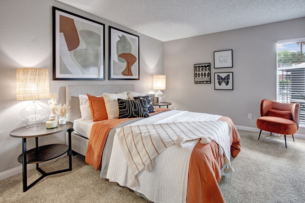 A bedroom with a large bed and a red chair.