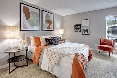 A bedroom with a large bed and a red chair.
