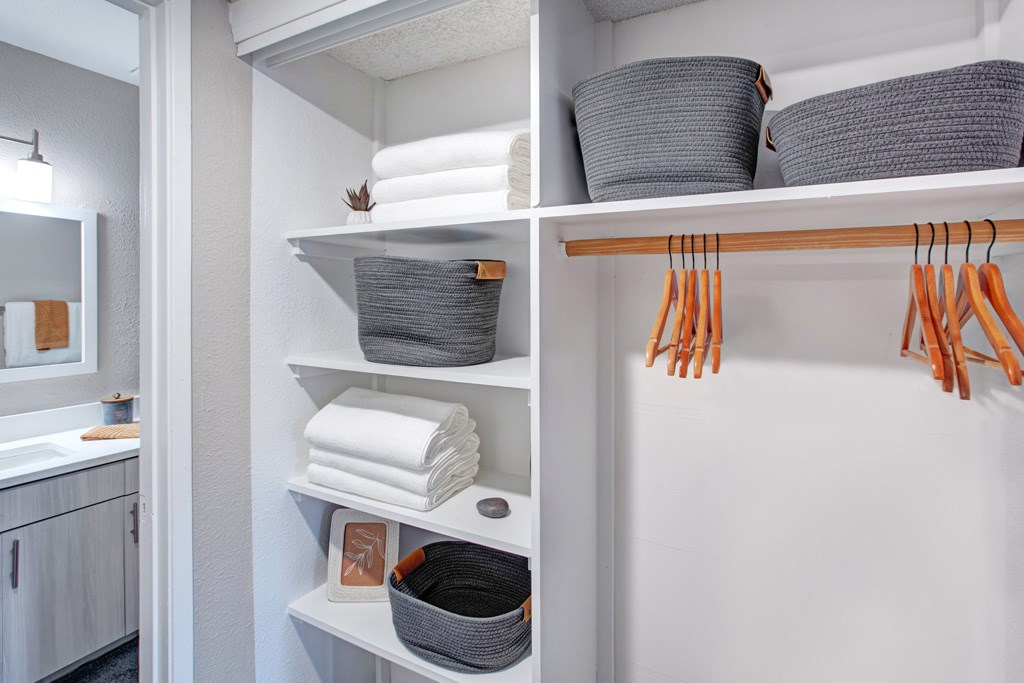 A bathroom with a white cabinet and a white shelf with towels and baskets.