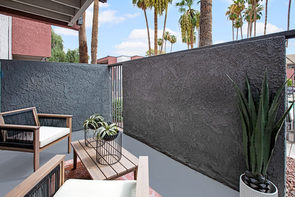 A patio with a table, chairs, and plants.