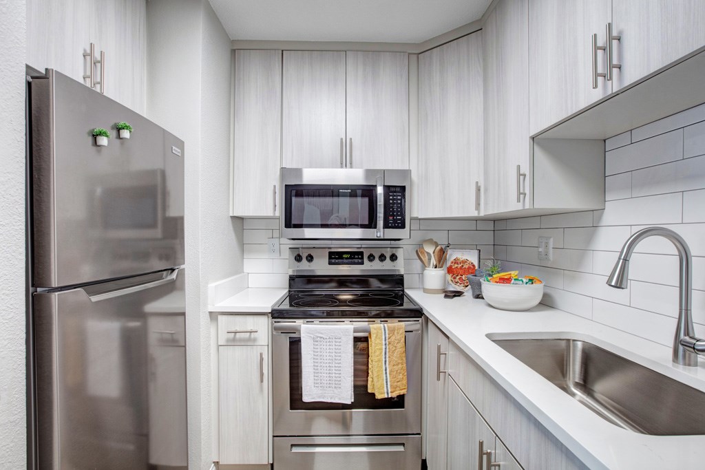 A modern kitchen with a stainless steel refrigerator and oven.
