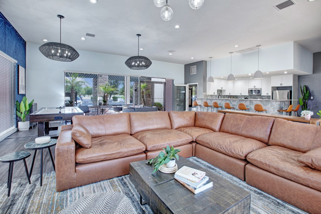 A brown leather sofa sits in a well-lit living room with a glass coffee table in front of it.