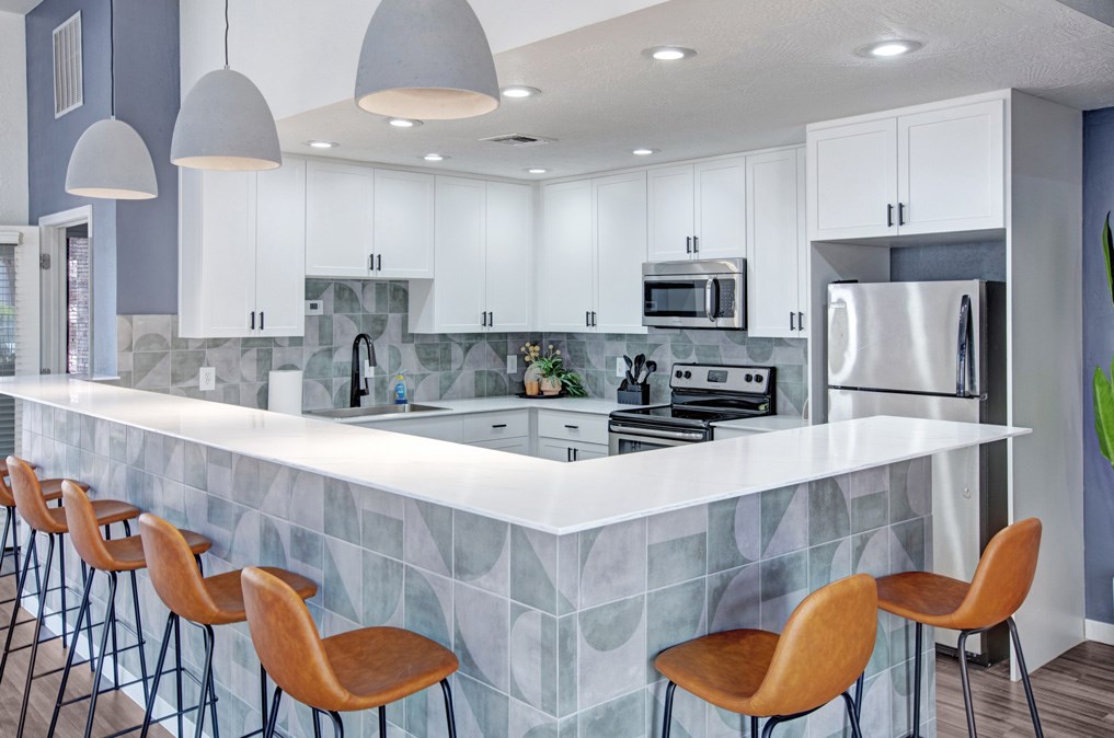 A kitchen with a white counter and wooden chairs.