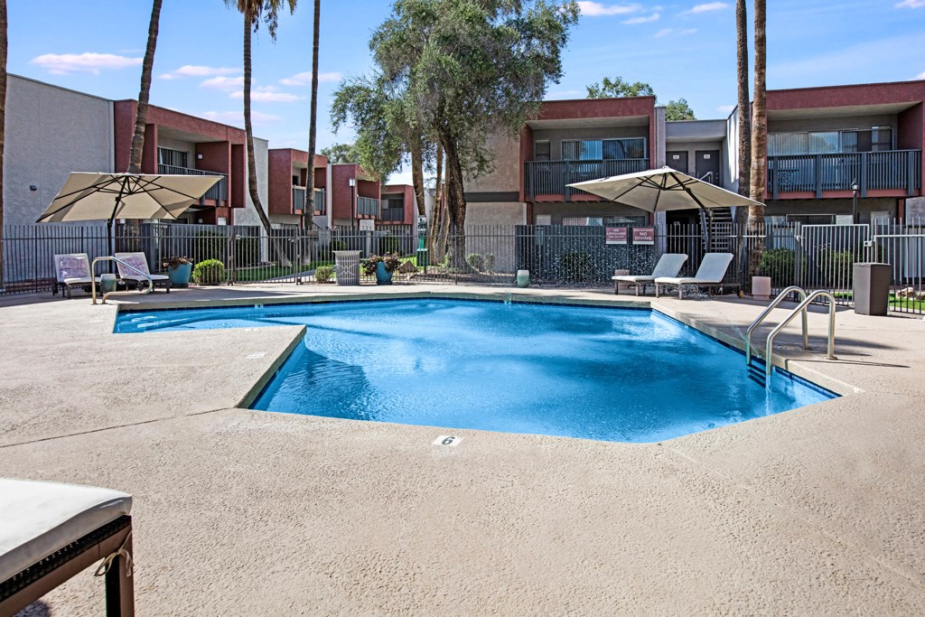 A swimming pool surrounded by a fence and trees.