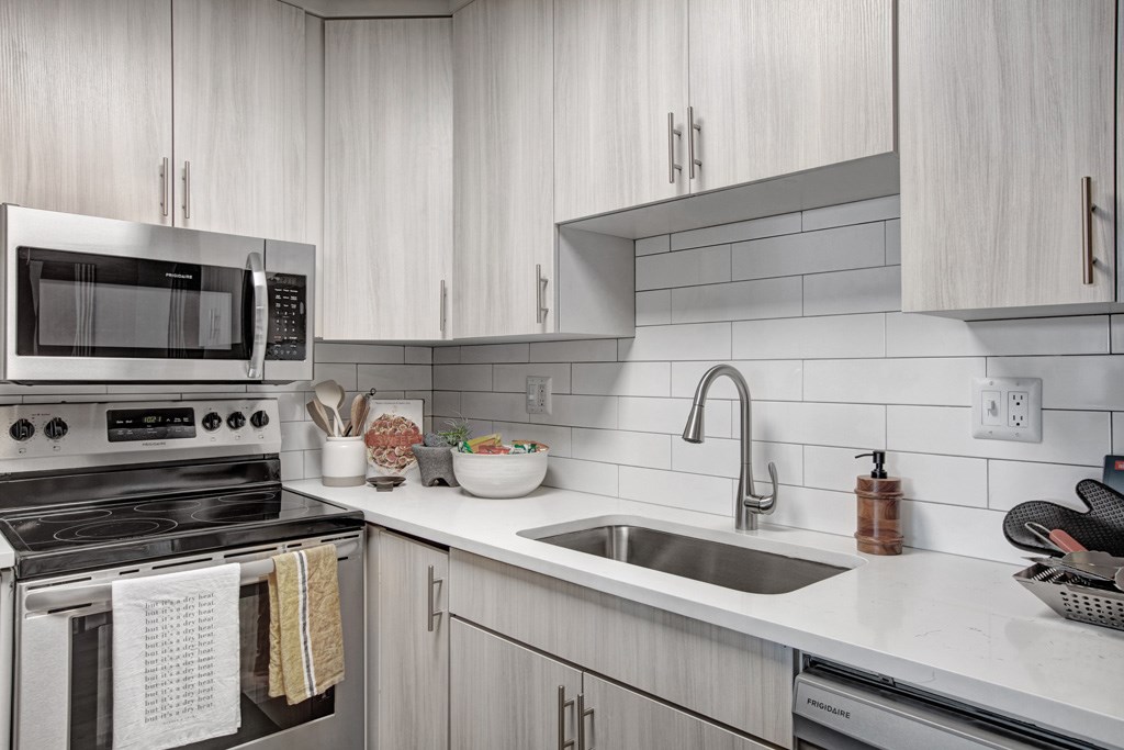 A modern kitchen with a stove, microwave, and sink.
