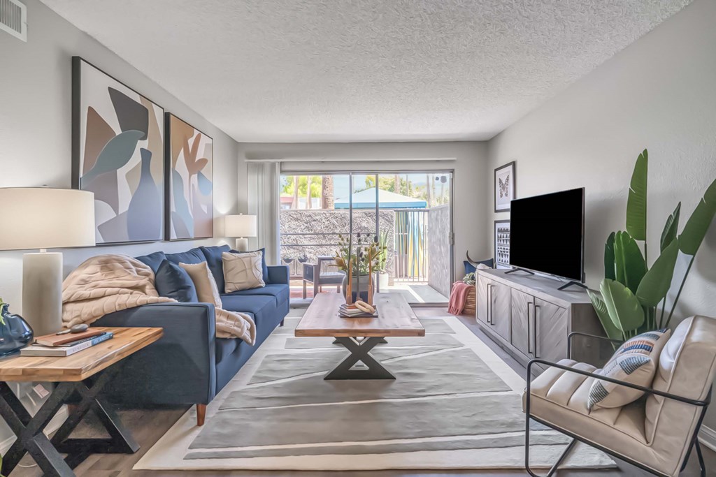 A living room with a blue couch, a wooden coffee table, and a flat screen TV.
