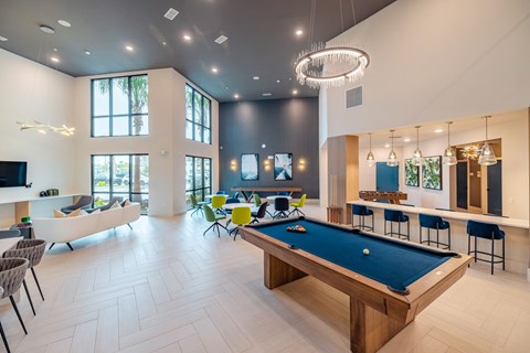 A pool table is in the middle of a room with a white couch and chairs.