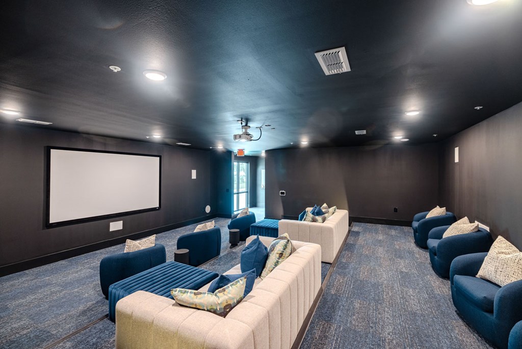 A room with a white screen and blue couches.