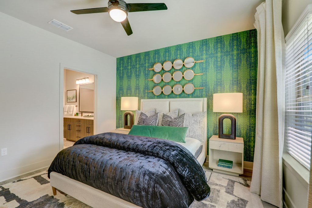 A bedroom with a bed, a ceiling fan, and a green accent wall.