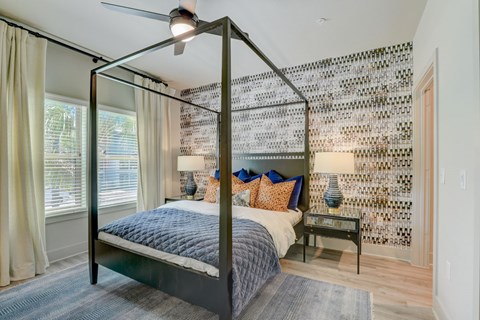 A bedroom with a four poster bed and a ceiling fan.