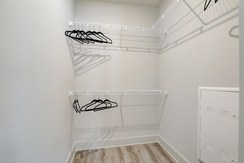 A white closet with two shelves and a white door.