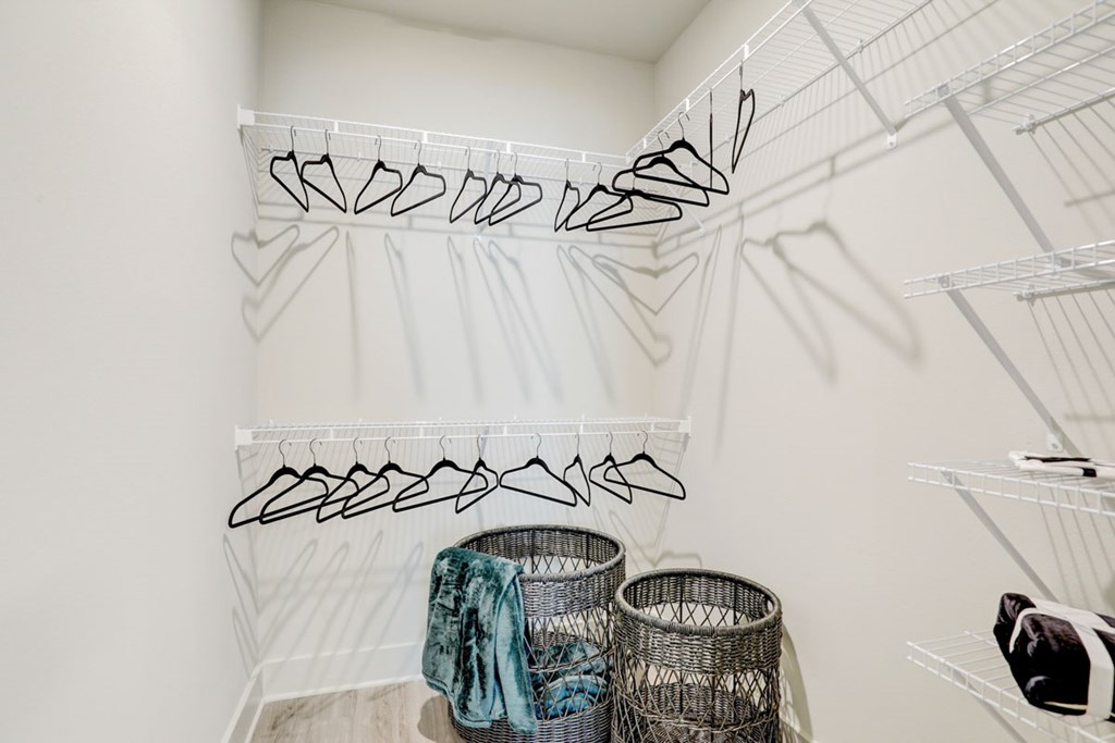 A white closet with clothes hanging on hangers.