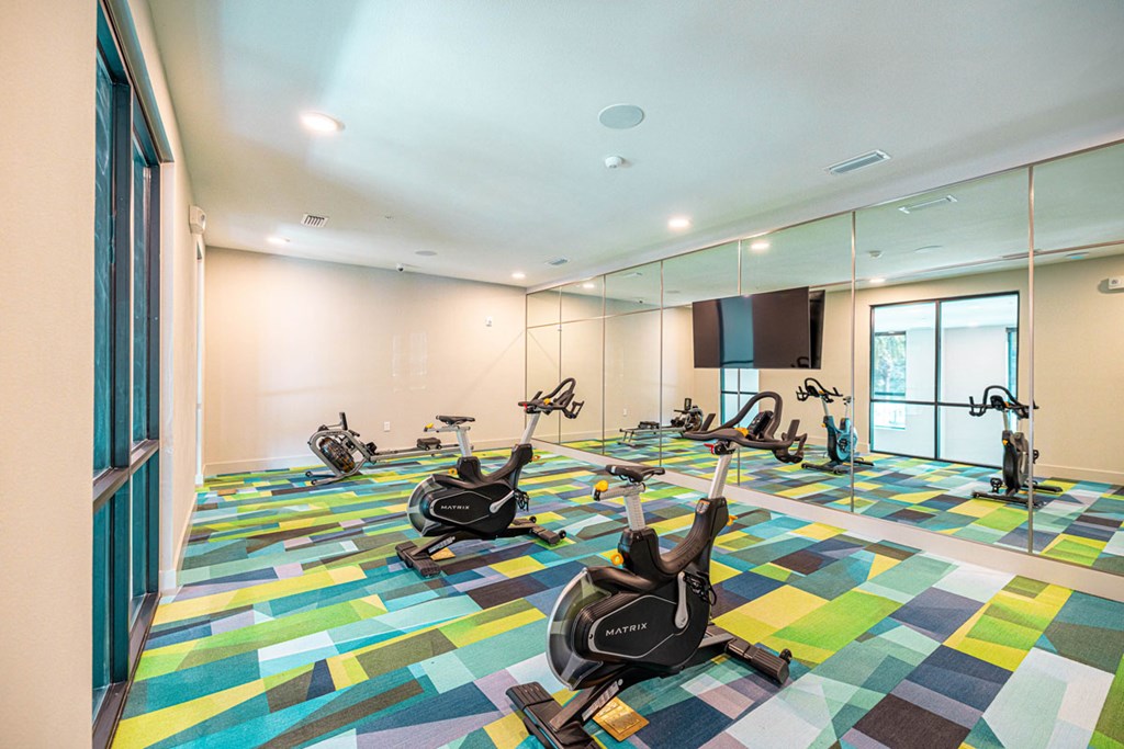 A room with exercise bikes on a colorful floor.