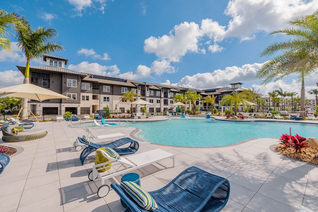 A large swimming pool surrounded by lounge chairs and palm trees.