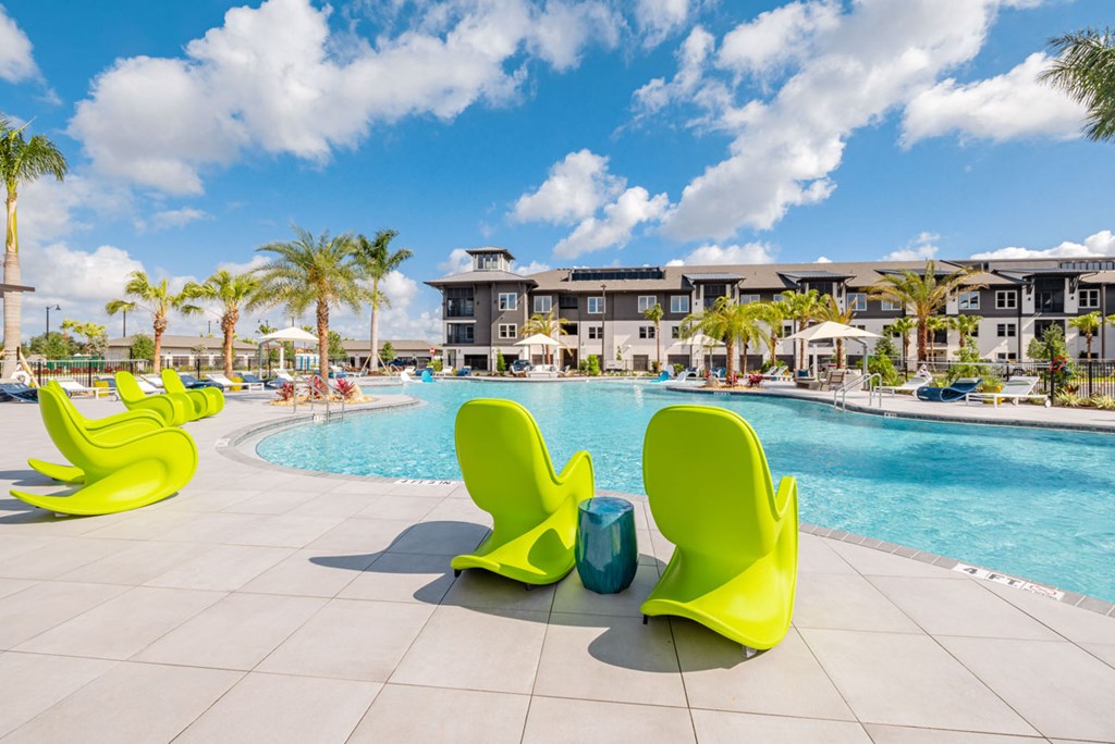 A pool area with bright yellow chairs and a blue pool.