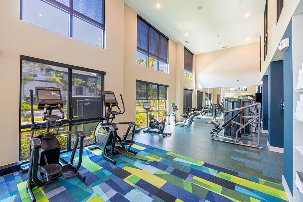 A gym with a variety of equipment including treadmills, weights, and exercise machines.