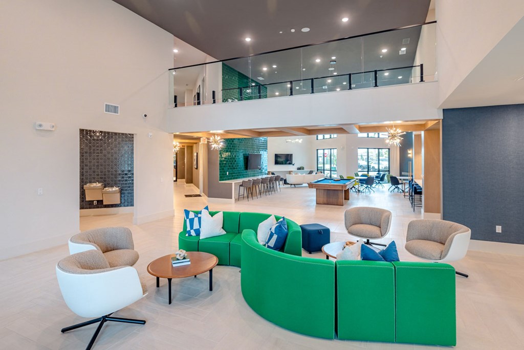 A living room with a green couch and white chairs.