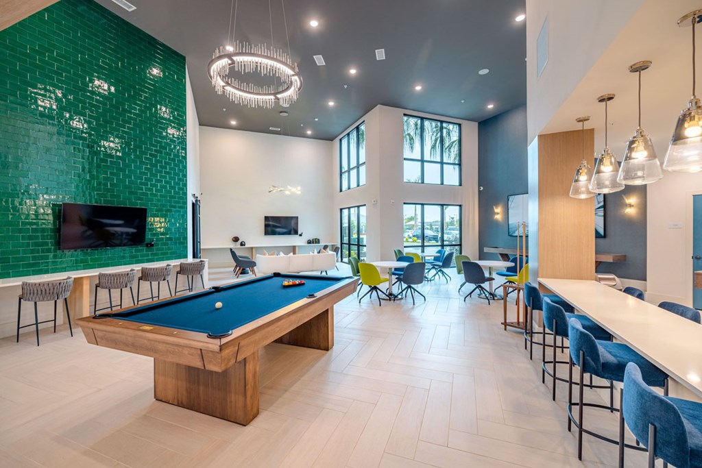 A room with a pool table and a green tiled wall.