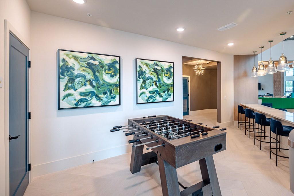 A modern dining room with a large wooden table and two paintings on the wall.
