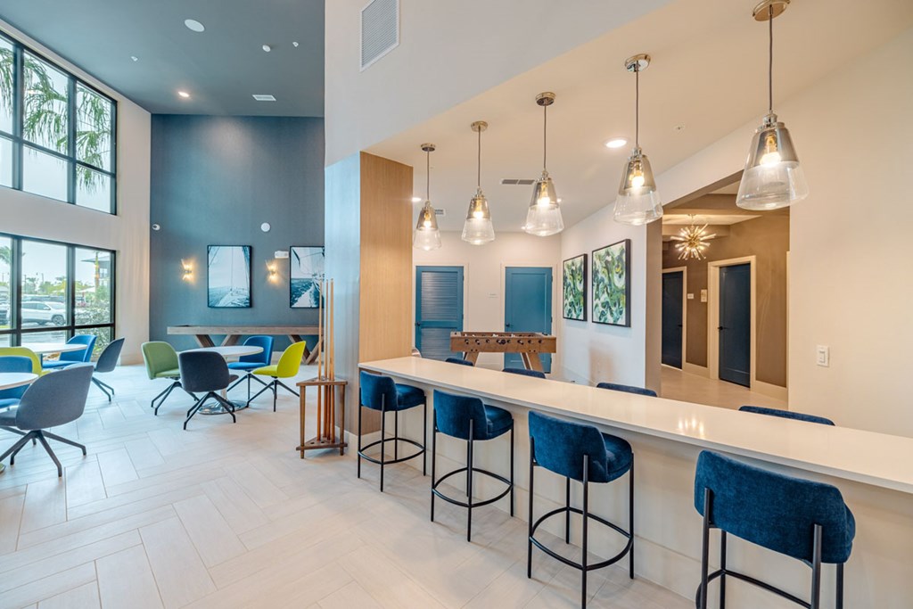 A modern bar area with blue bar stools and a long white counter.