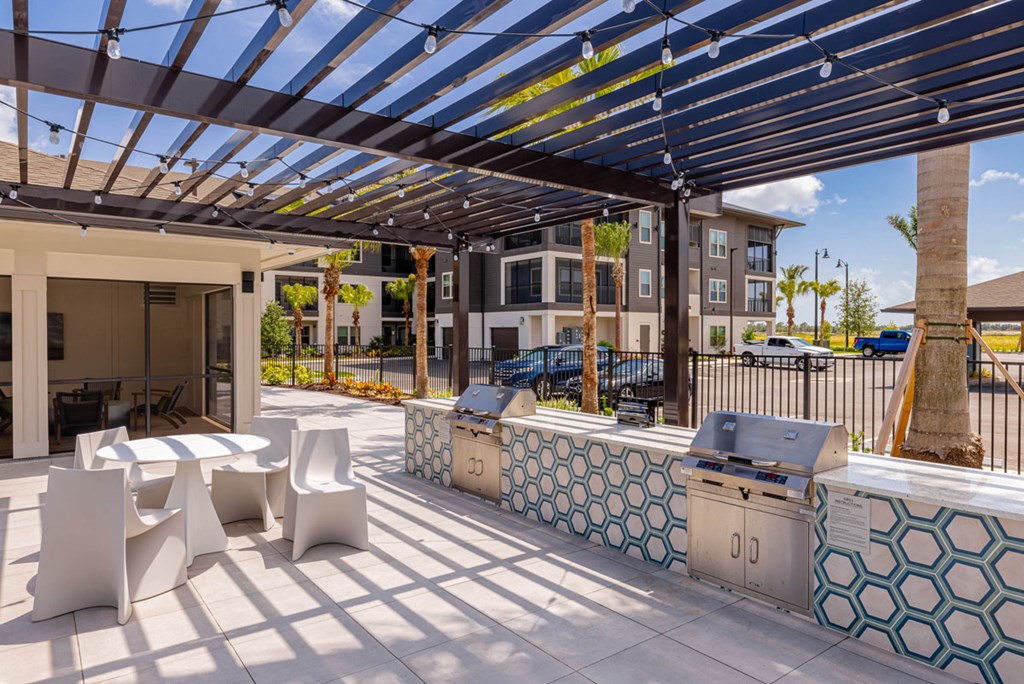 A patio with a white table and chairs under a striped awning.