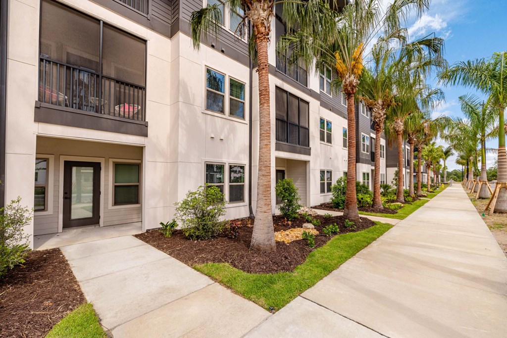 A row of modern apartment buildings with balconies and palm trees.