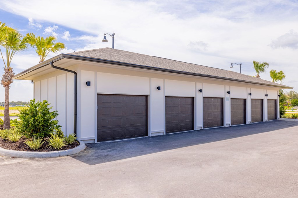 A white building with a black roof and a row of garage doors.