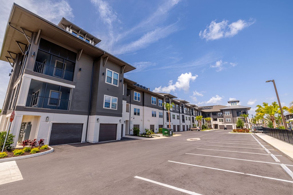 A large, modern apartment complex with a spacious parking lot in front.