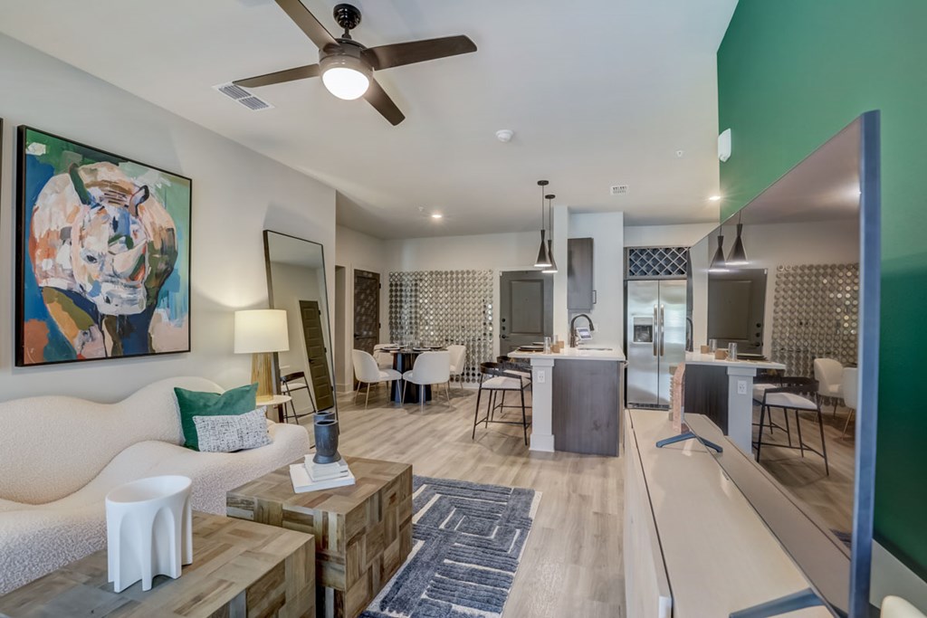 A modern living room with a large painting on the wall and a dining area in the background.