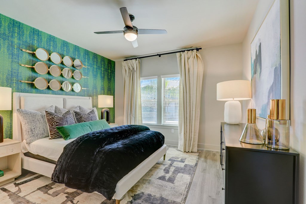 A bedroom with a bed, a ceiling fan, and a wall with circular decorations.