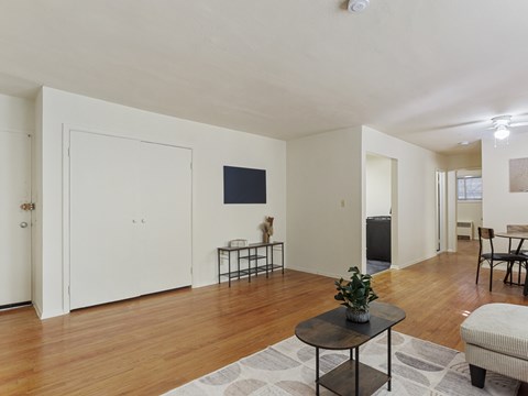 A living room with a wooden floor and a television on the wall.