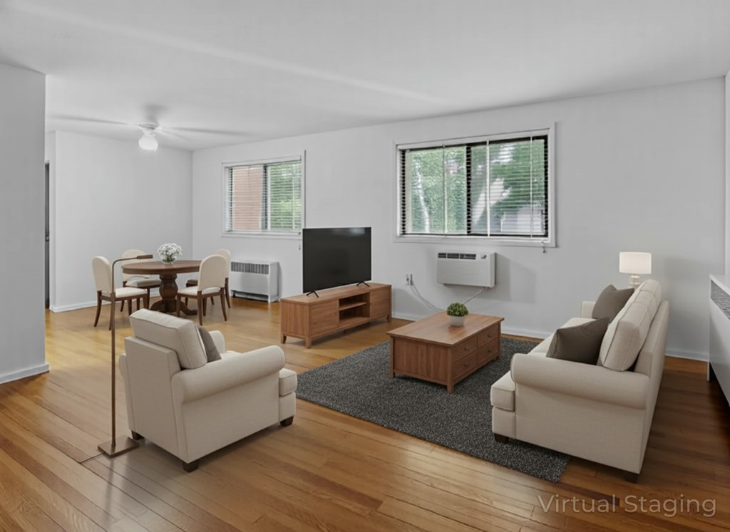 A living room with a television, two chairs, a table, and a rug.