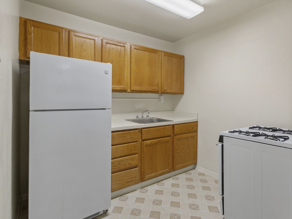 A kitchen with a white refrigerator, wooden cabinets, and a white stove.