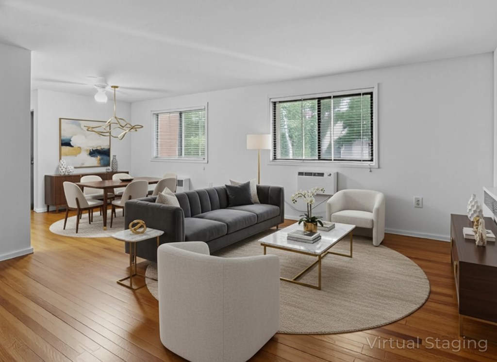 A living room with a grey couch, a white armchair, a coffee table, and a painting on the wall.