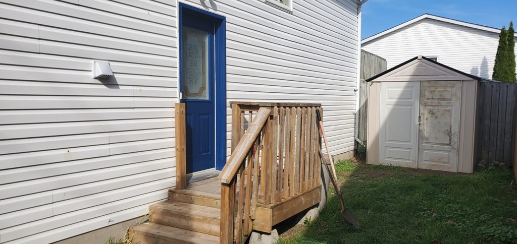 A blue door is on the left side of a white house.
