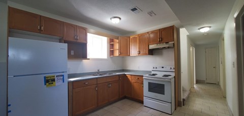 A kitchen with brown cabinets and a white fridge.