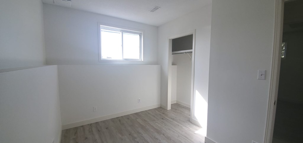 A room with a window and a door is empty and waiting to be furnished.