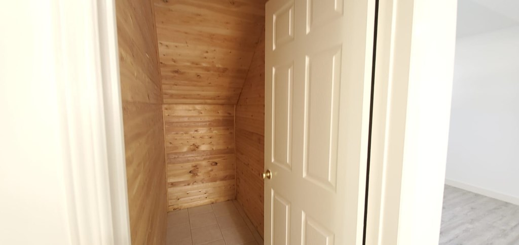 A white door is in a room with wooden walls.