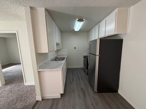 A kitchen with a black refrigerator and white cabinets.